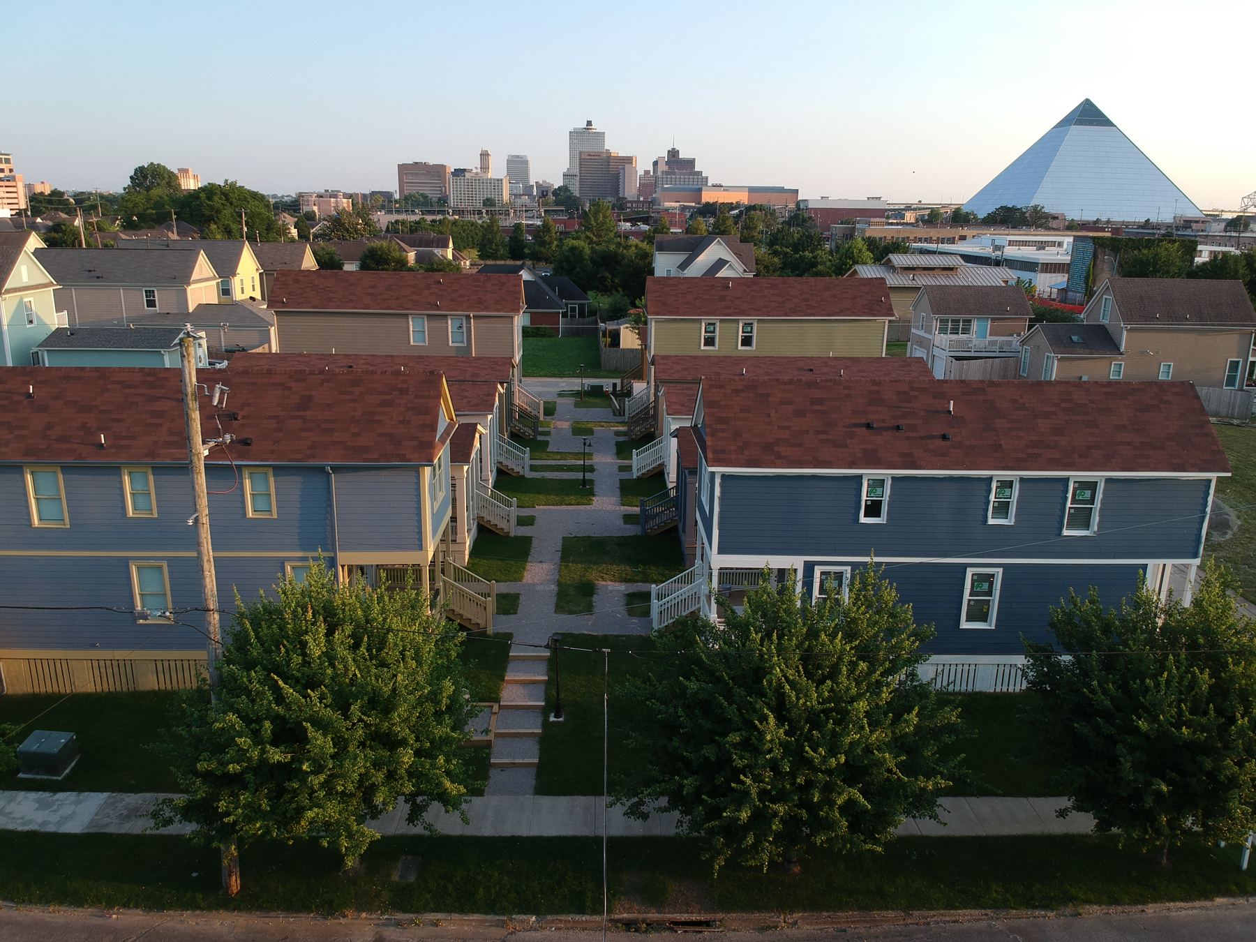 Aerial view of Malone Park Commons in Uptown Memphis, cottages and fourplexes around a shared green with the downtown skyline behind