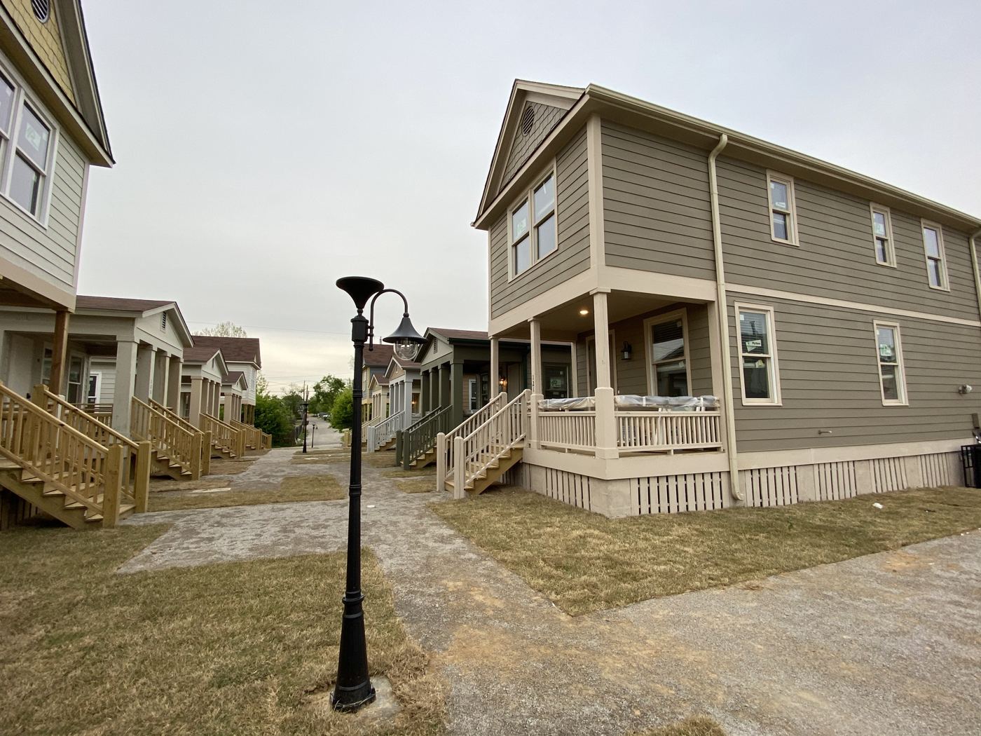 A pedestrian walk between cottages at Malone Park Commons with porches on both sides