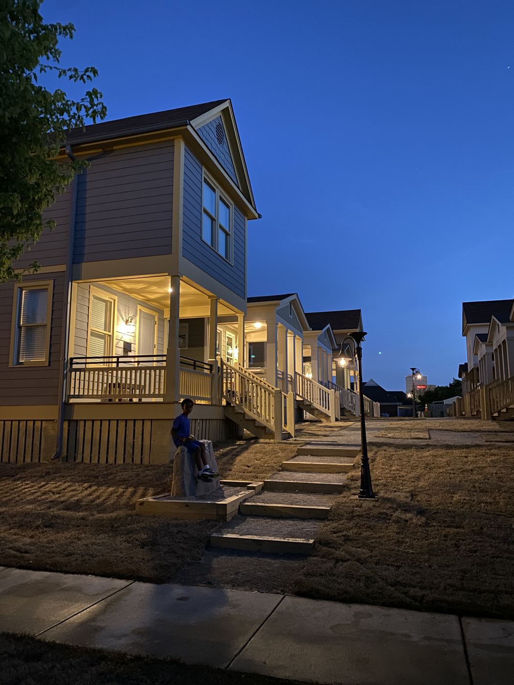 A cottage porch at dusk at Malone Park Commons